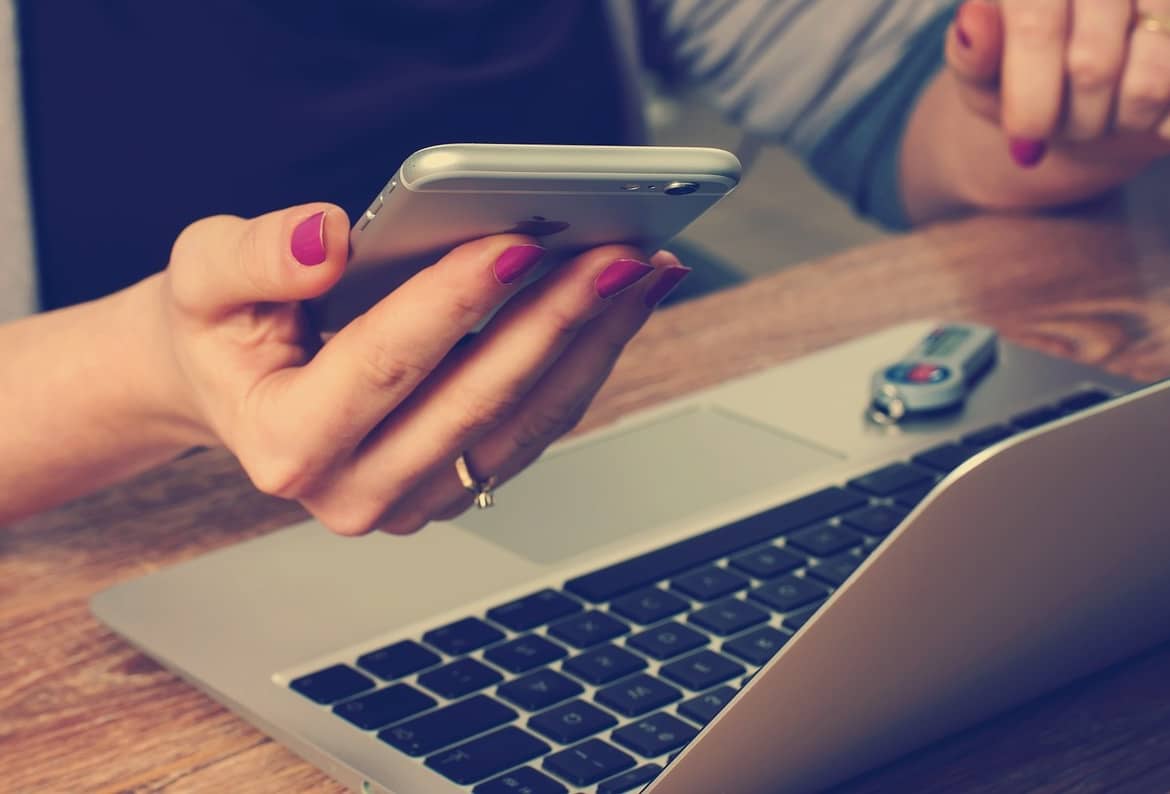 a woman holding an iphon with laptop in front