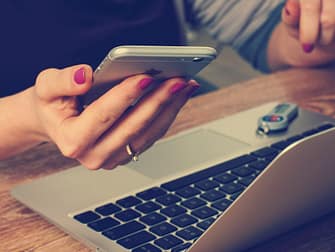 a woman holding an iphon with laptop in front