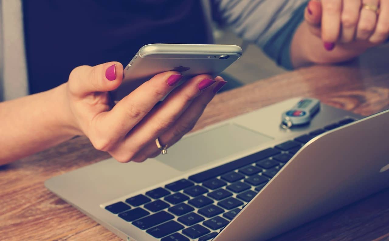 a woman holding an iphon with laptop in front